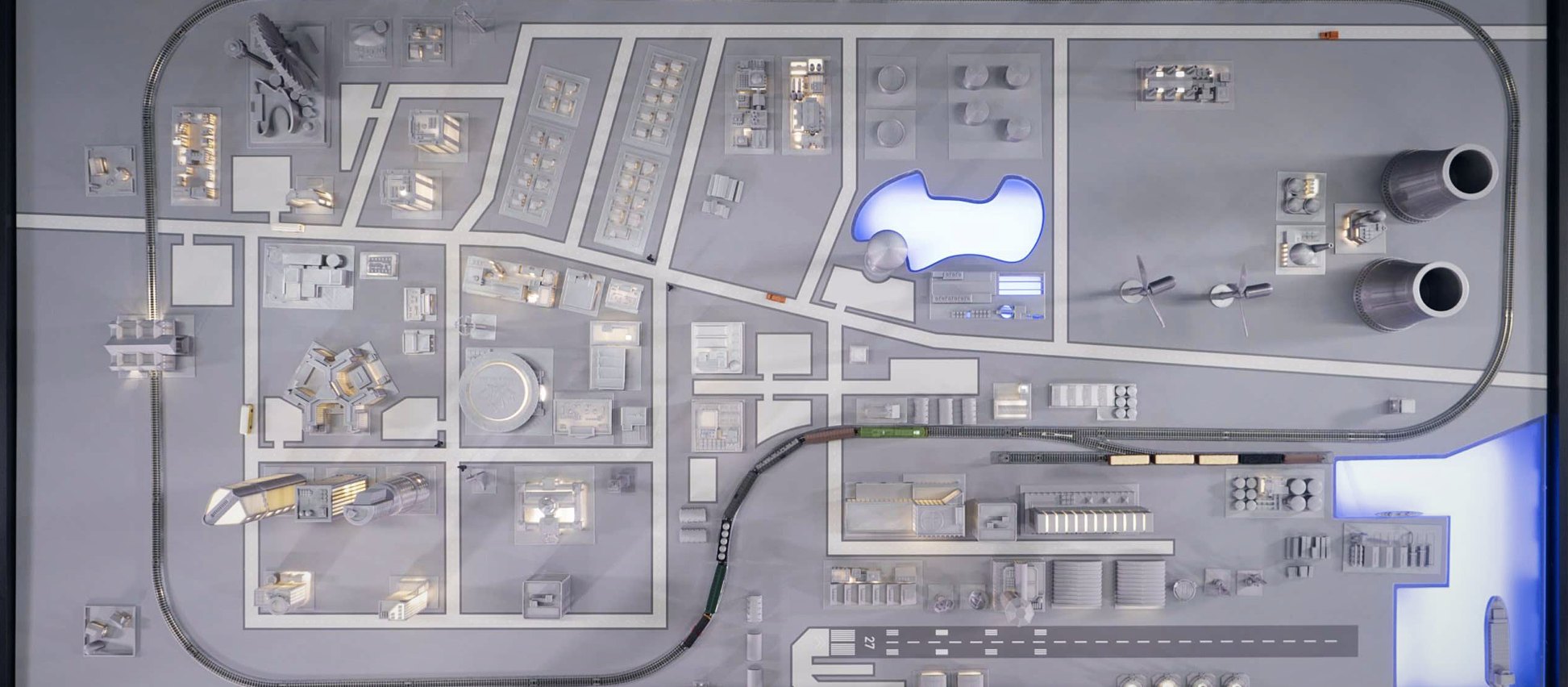 Top view of a city-scale training model with power plant, rail loop, downtown, port, and runway